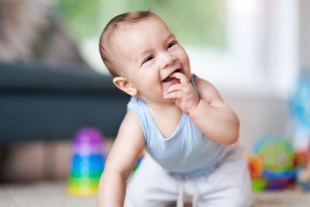 schattige lachende babyjongen die op de vloer in de woonkamer kruipt