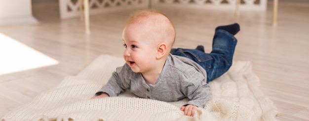 Schattige lachende babyjongen in zonnige slaapkamer