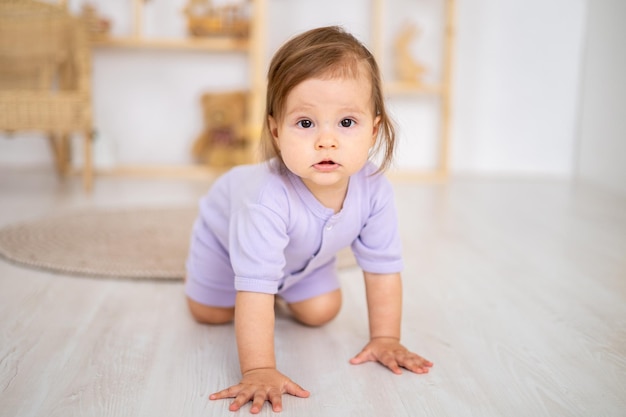 Schattige lachende gezonde babymeisje in paarse bodysuit spelen in de kinderkamer thuis educatief speelgoed voor kinderen