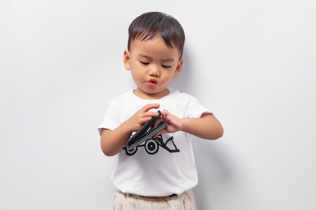 Schattige lachende jonge Aziatische jongen jongen 2 jaar oud dragen van een witte t-shirt portemonnee in de hand geïsoleerd op een witte achtergrond