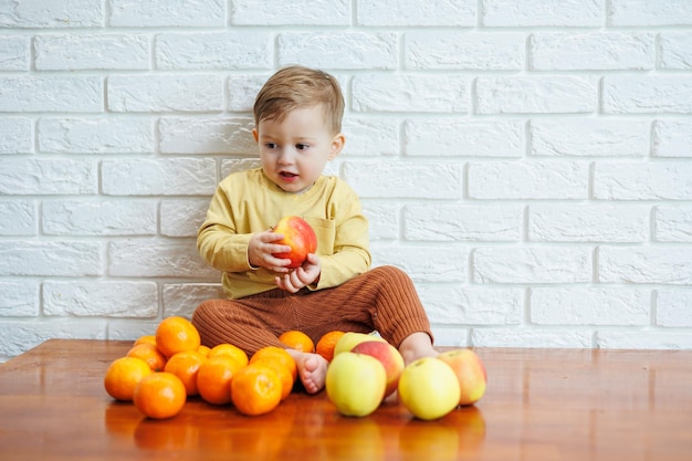 Schattige lachende jongen die een verse, sappige rode appel eet. Gezond fruit voor jonge kinderen