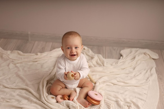 schattige lachende jongen spelen met een houten piramide op een witte sprei