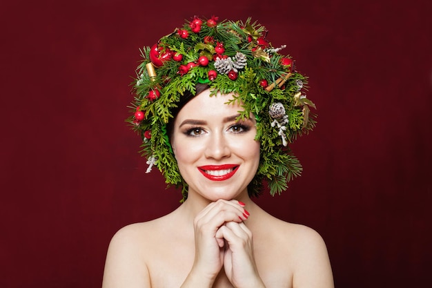 Schattige lachende vrouw in kerst decor op rode achtergrond