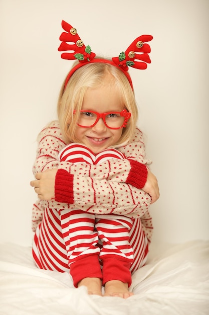 Schattige lgirl in kerst rendier gewei is opgewonden op witte achtergrond, kerstvakantie