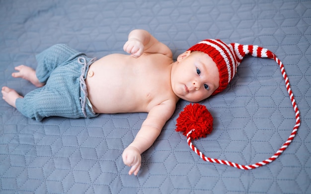 Schattige lieve baby in een hoed met pompon Vrij grappige jongen in hoed liggend op deken