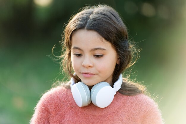 Schattige melomane Klein meisje met koptelefoon Gelukkig kind geniet van het luisteren naar muziek onderweg Schattig klein meisje buiten Alles wat ze wil horen is muziek
