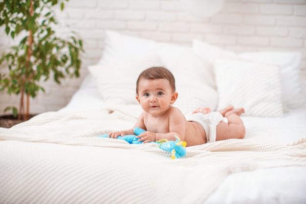 Schattige mollige baby ligt op zijn buik en kijkt weg