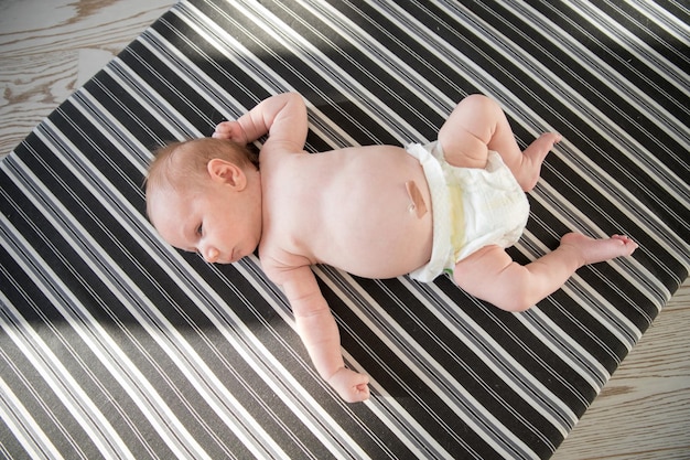 Schattige pasgeboren baby in een luier liggend op een bed op gestreepte lakens