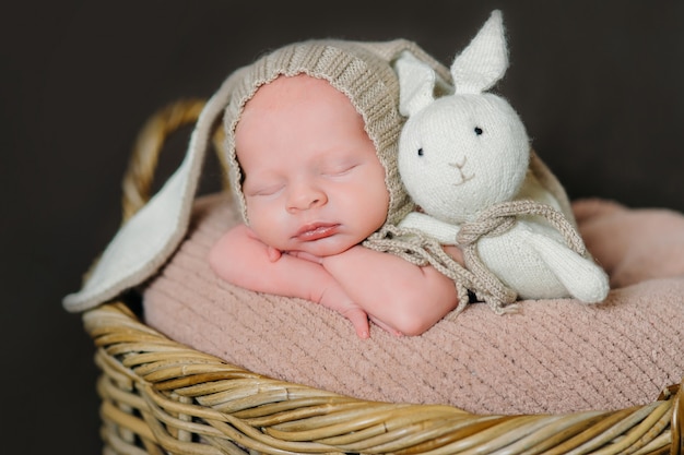 Schattige pasgeboren baby ligt op een houten achtergrond, gekleed in konijn kostuum. Paasvakantie. Landschap in de rustieke stijl