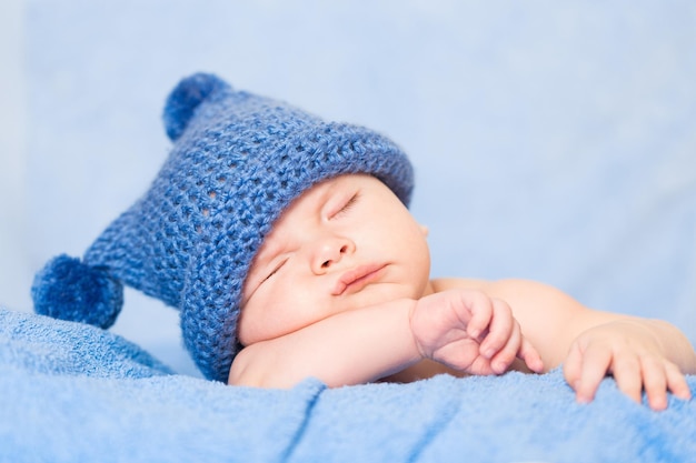 Schattige pasgeboren baby slapen op bed met hoed, close-up