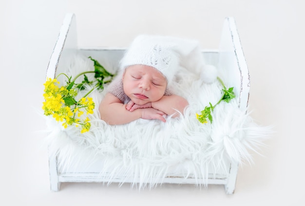 Schattige pasgeboren babyjongen slapen op zijn buik in wit houten bed