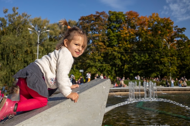 Schattige peuter beklimt de fontein in het park weekendwandeling met kinderen in het park op goede dag