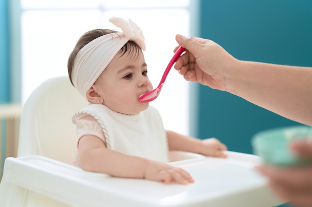 Schattige peuter die pap eet terwijl hij thuis op een kinderstoel zit