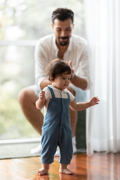 Schattige peuter klein kind familie concept baby leren lopen met vader en moeder om te helpen zorgen en hand te houden eerste stap met kindertijd ouder ondersteuning kleine liefde portret jongetje thuis