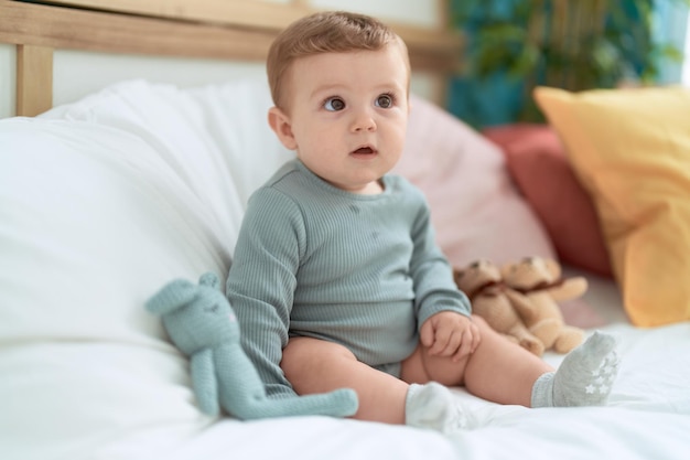 Schattige peuter zittend op bed met poppen in de slaapkamer