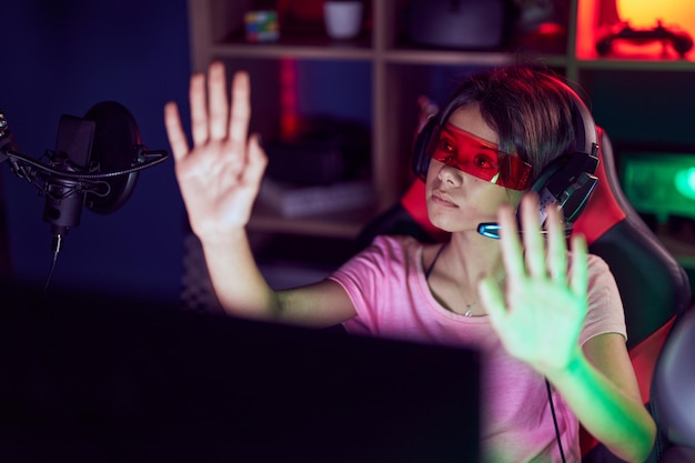 Schattige Spaanse meisjesstreamer die een videogame speelt met een virtual reality-bril in de speelkamer