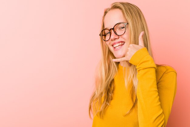 Schattige tienervrouw die een gebaar van het mobiele telefoongesprek met vingers toont.