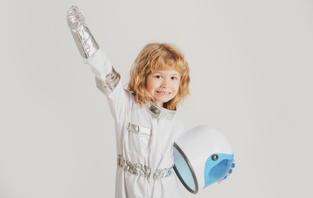 Schattige verbaasde jongensastronaut in de ruimte Kind stelt zich voor dat hij een astronaut is die een helm vasthoudt