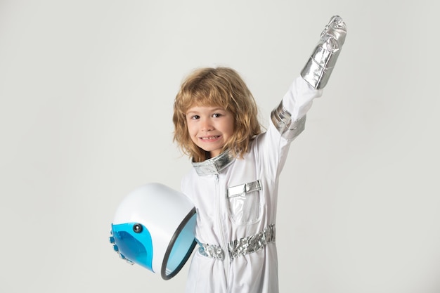 Schattige verbaasde jongensastronaut in de ruimte Kind stelt zich voor dat hij een astronaut is die een helm vasthoudt