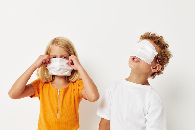 Schattige voorschoolse kinderen in medische maskerbescherming poseren grimas geïsoleerde achtergrond ongewijzigd