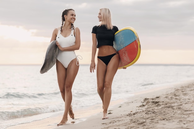 schattige vriendinnen met surfplank op het strand