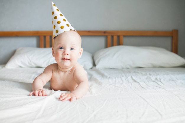 Schattige vrolijke baby in een feestelijke cap op zijn hoofd