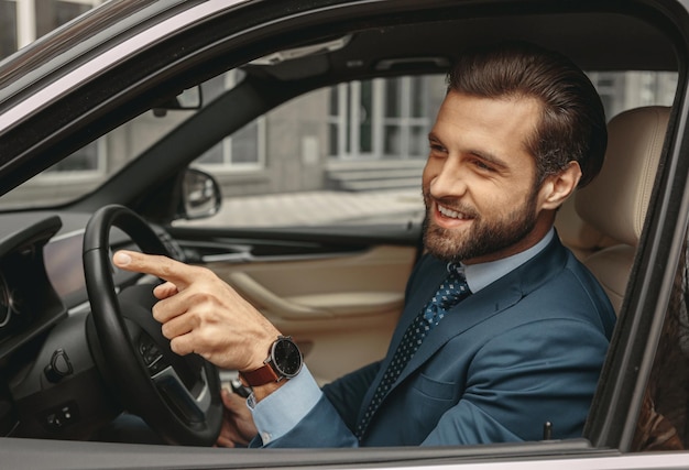 Schattige zelfverzekerde man in formele kleding gebaren in de auto