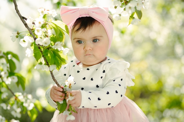 Schattige zes maanden oude baby met kersenbloesem tak in het voorjaar