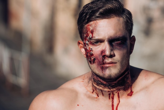 Schedel make-up portret van jonge man. naakte man met griezelige gesneden halloween-pompoen. close-up portret van een man met zombie make-up. bloedige naakte man met hoofdletsel, bloederig thema, halloween-thema.