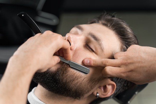 Scheermes gesneden man baard in kapperszaak. kapper man kapsel maken voor knappe man.