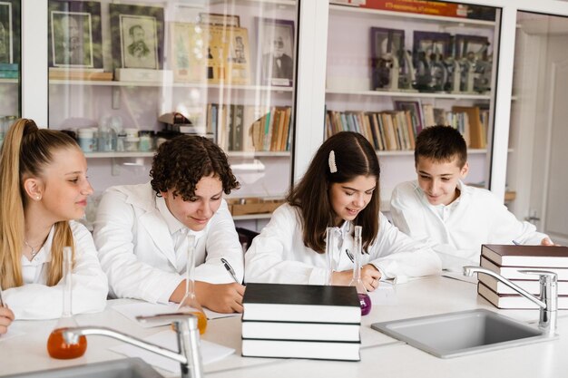 Scheikundeles in het laboratorium op school Leerlingen schrijven huiswerk lachend en hebben plezier samen in het schoollaboratorium