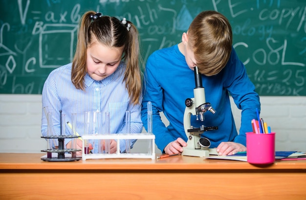 Scheikundeles op school Schoollaboratorium Schoolonderwijs Meisje en jongen communiceren terwijl ze een schoolexperiment uitvoeren Kinderen studeren samen klaslokaal Chemische analyse Kinderen studeren chemie