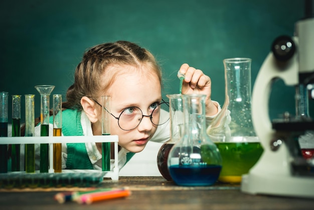 Scheikundelessen op school Kind in de klas met schoolbord op achtergrond Schoolconcept Scheikundewetenschap Biologie-experimenten met microscoop