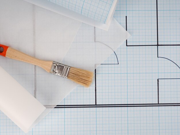 Schematic plan of the apartment, drawing on millimeter paper in a roll, near the brush Builder concept of repair and design. House plan, cozy housing, building construction, new building.