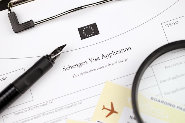 Schengen visa application on a tablet lies on office table with pen and magnifying glass