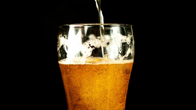 schenkt bier in een glas op een donkere achtergrond