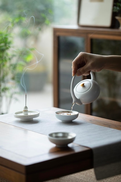 Schenkt thee uit een theepot in een kopje Rustig thee drinken in de ochtend om de hele dag energie te hebben