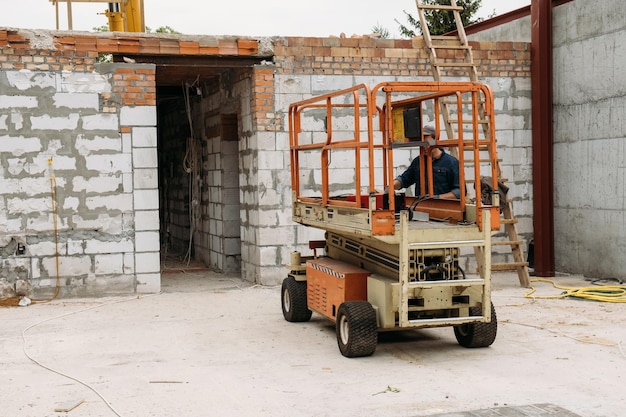 Scherenliftplatform op een bouwterrein voor het bouwen van een betonhuis met mobiel vervoer