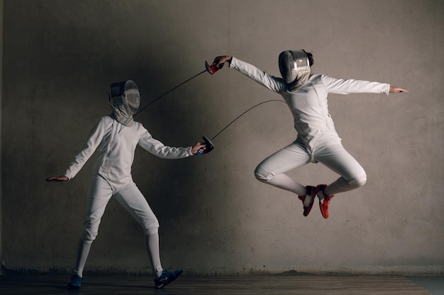 Schermers vrouwen met schermzwaard Schermers duel steek aanval en jumpconcept