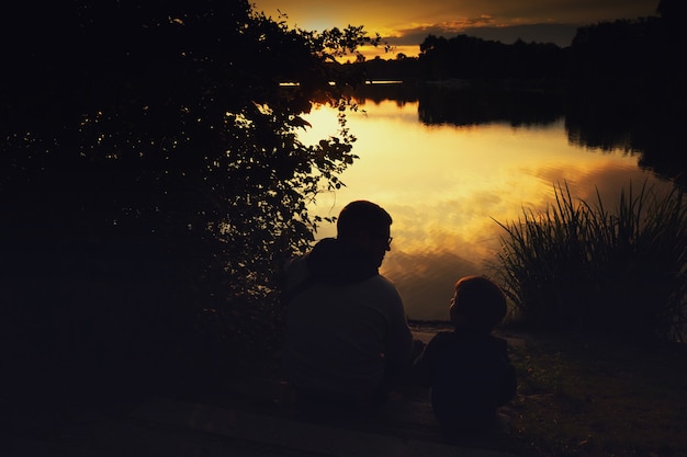 schets van een jongen met papa bij zonsondergang op het meer