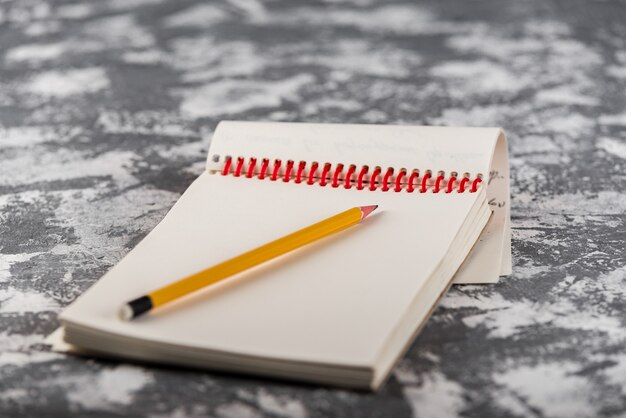 Schetsboek Kladblok met houtpotlood op stenen tafel Bureau achtergrond, loft-stijl, concept en idee om hier uw tekst te schrijven.