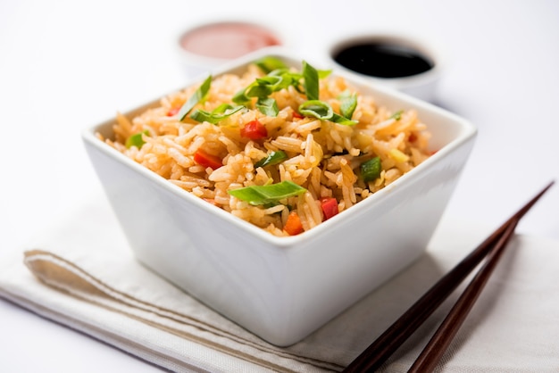 Schezwan Fried Rice Masala is a popular indo-chinese food served in a plate or bowl with chopsticks. selective focus