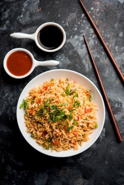 Жареный рис Масала - популярное индокитайское блюдо, которое подают в тарелке или миске с палочками для еды. выборочный фокус