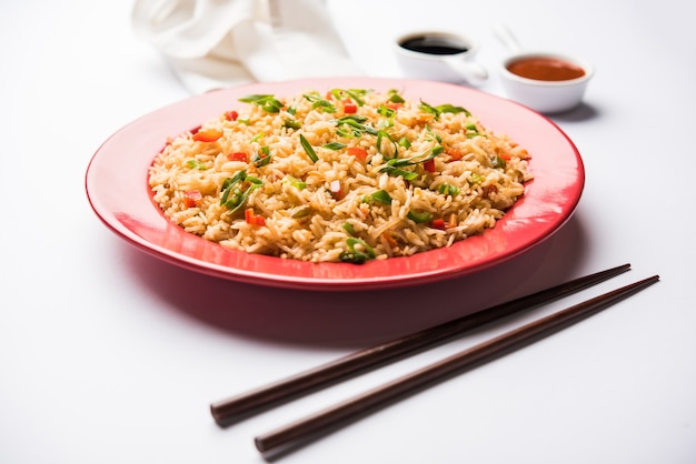 Schezwan Fried Rice Masala is a popular indo-chinese food served in a plate or bowl with chopsticks. selective focus