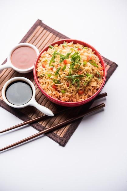 Schezwan Fried Rice Masala is a popular indo-chinese food served in a plate or bowl with chopsticks. selective focus