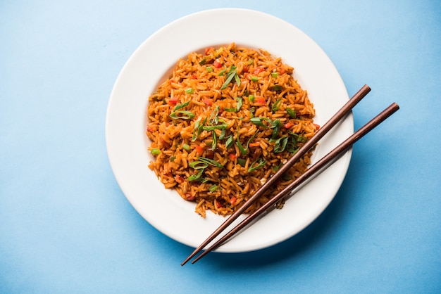 Schezwan Fried Rice Masala is a popular indo-chinese food served in a plate or bowl with chopsticks. selective focus