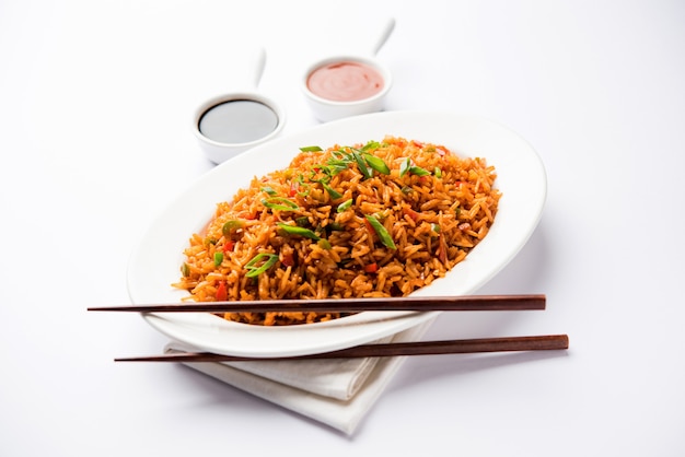 Schezwan Fried Rice Masala is a popular indo-chinese food served in a plate or bowl with chopsticks