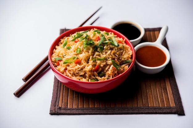 Schezwan Fried Rice Masala is a popular indo-chinese food served in a plate or bowl with chopsticks