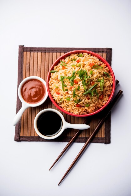 Schezwan Fried Rice Masala is a popular indo-chinese food served in a plate or bowl with chopsticks