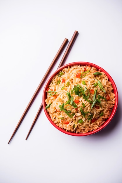 Schezwan Fried Rice Masala is a popular indo-chinese food served in a plate or bowl with chopsticks